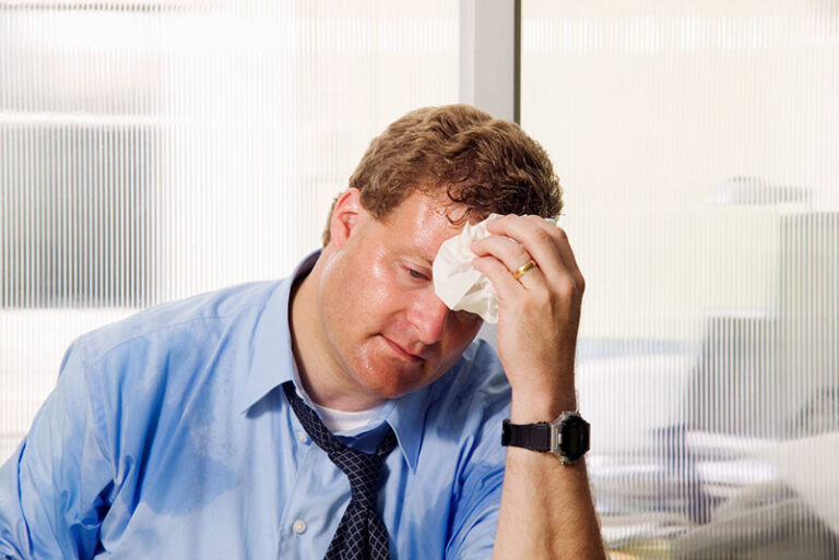 man holding wet cloth to forehead